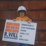 Kleines Kind mit einem Schild von Bauunternehmen Will